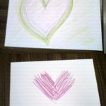 柔らかいピンクのハートと赤のV字型のアートセラピー作品